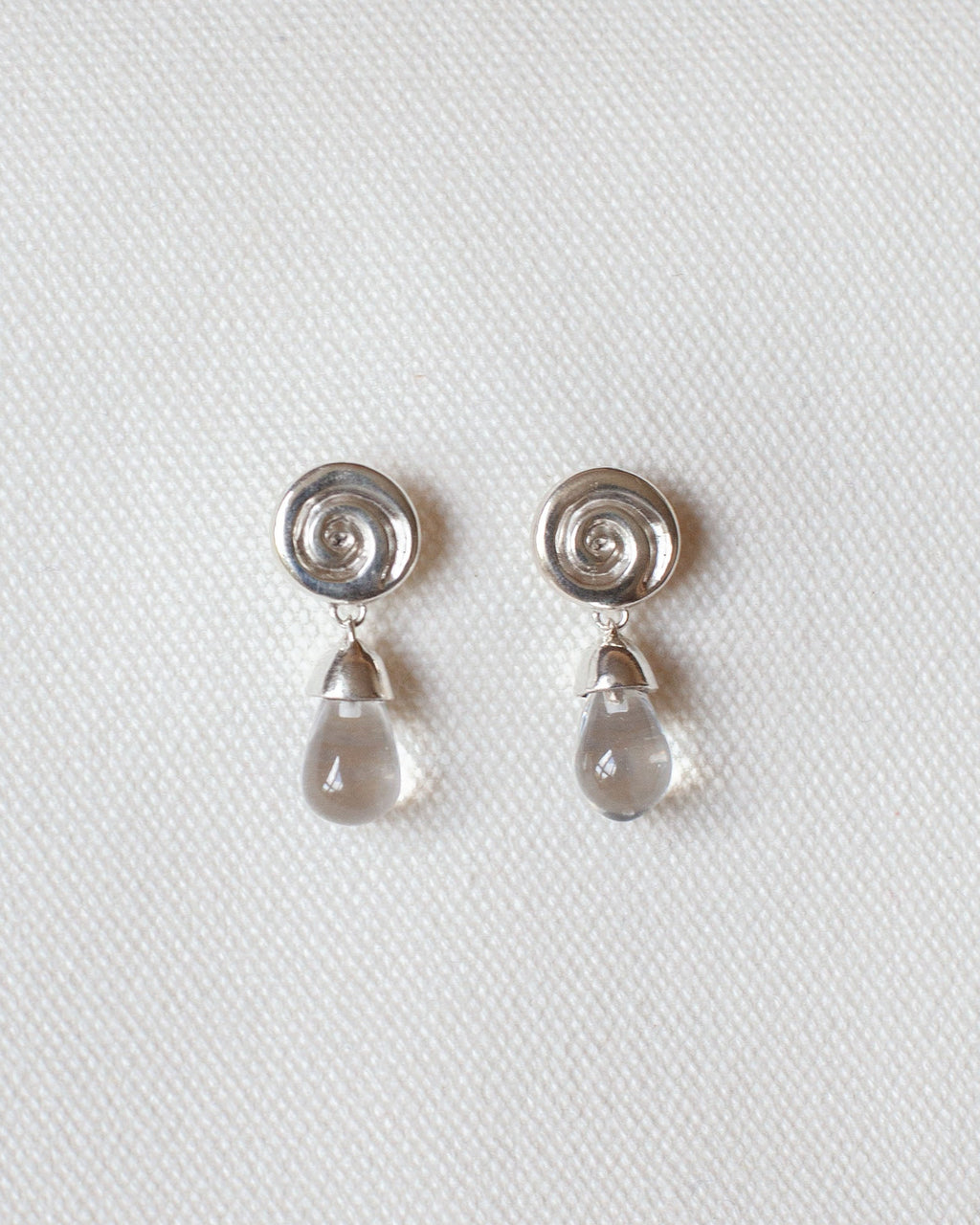 pair of silver earrings with spiral design and crystal quartz drops
